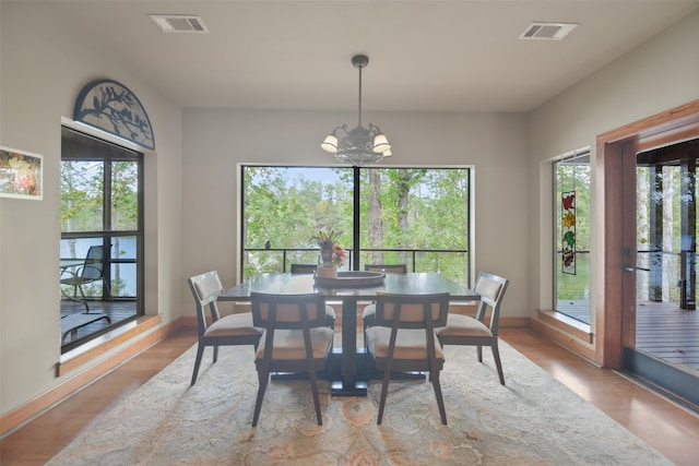 dining space featuring a wealth of natural light, an inviting chandelier, and light wood-type flooring