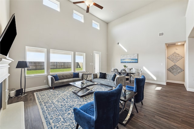 living room featuring dark wood-type flooring, a high ceiling, and ceiling fan