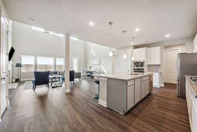 kitchen with a kitchen island with sink, hanging light fixtures, stainless steel appliances, dark hardwood / wood-style flooring, and ceiling fan