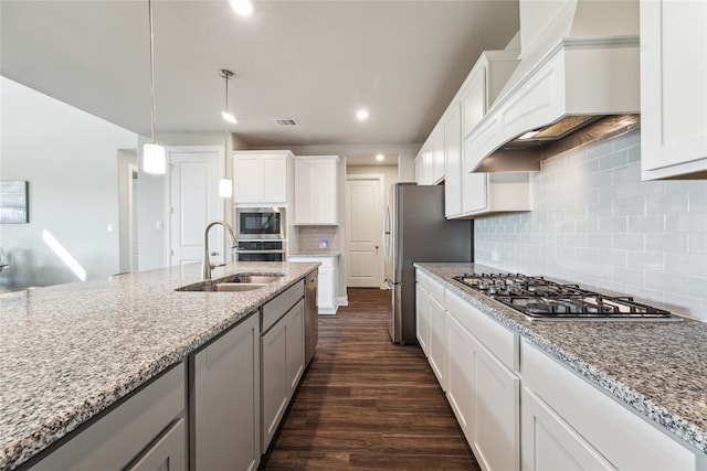 kitchen with appliances with stainless steel finishes, sink, custom exhaust hood, white cabinets, and dark wood-type flooring