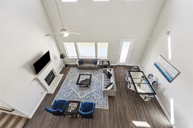 living room with a high ceiling, dark hardwood / wood-style floors, and ceiling fan