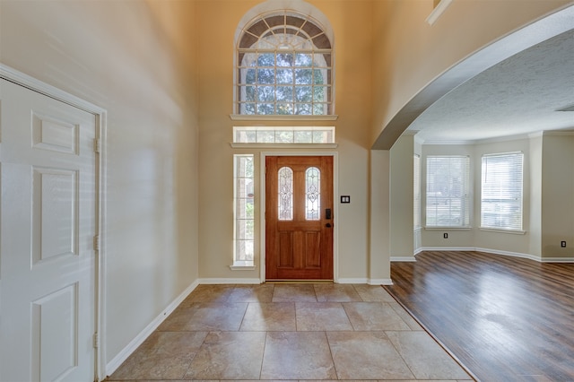 foyer featuring light hardwood / wood-style floors, a healthy amount of sunlight, a textured ceiling, and crown molding