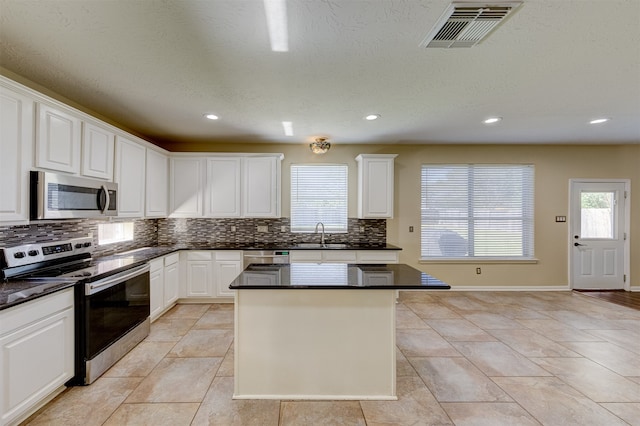 kitchen with appliances with stainless steel finishes, white cabinets, and plenty of natural light