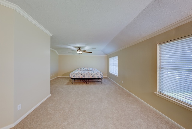 unfurnished bedroom featuring lofted ceiling, crown molding, light carpet, and ceiling fan