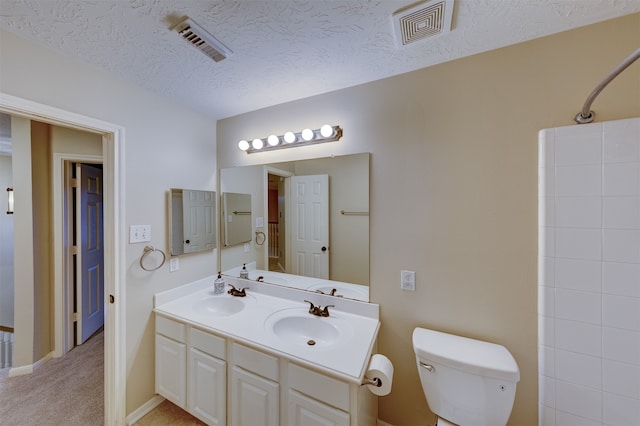 bathroom with vanity, toilet, a textured ceiling, and a shower