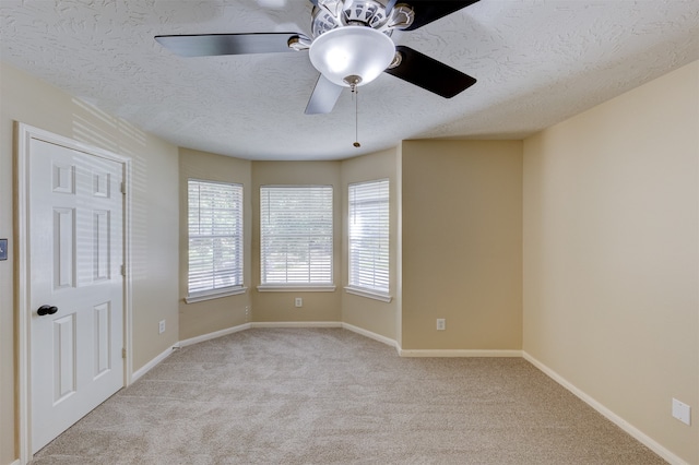 empty room featuring light carpet, a textured ceiling, and ceiling fan