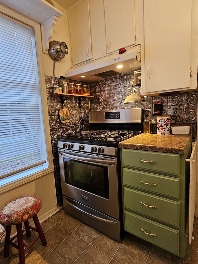 kitchen with white cabinets, decorative backsplash, dark tile patterned floors, and stainless steel range with gas cooktop