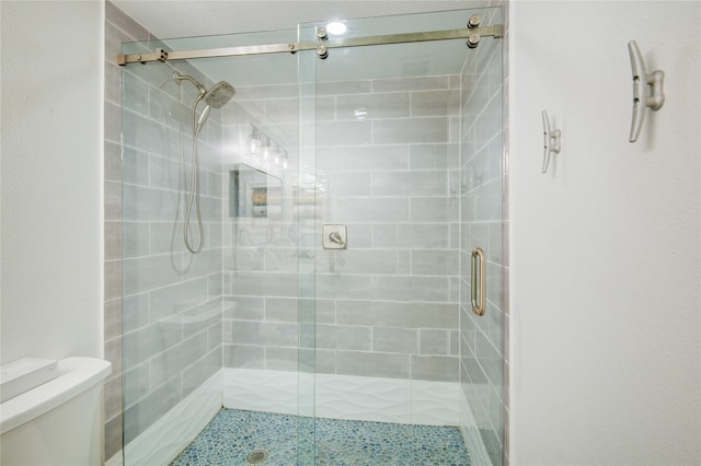 bathroom featuring toilet and a shower with shower door