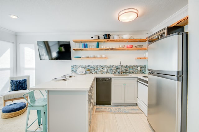 kitchen with sink, a kitchen bar, kitchen peninsula, stainless steel fridge, and white cabinets