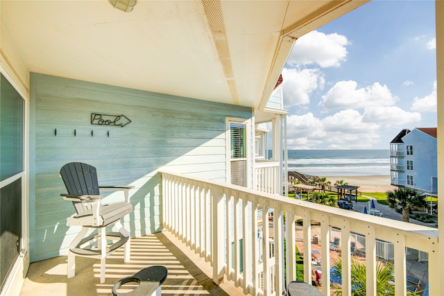 balcony with a water view and a view of the beach