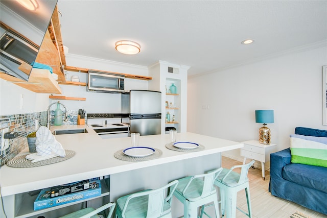 kitchen featuring appliances with stainless steel finishes, sink, kitchen peninsula, crown molding, and a breakfast bar