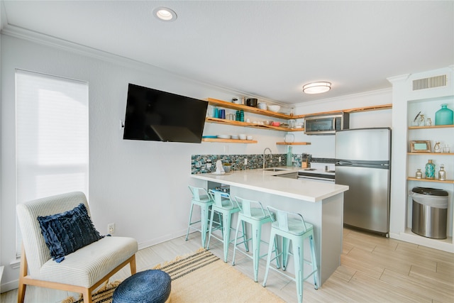 kitchen featuring a breakfast bar area, kitchen peninsula, stainless steel appliances, sink, and crown molding