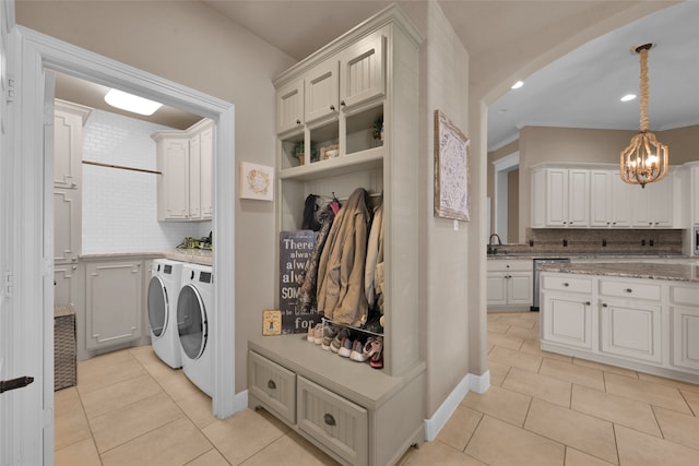 washroom featuring cabinets, light tile patterned floors, washer and dryer, a notable chandelier, and sink