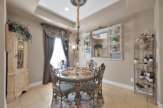 tiled dining space with a tray ceiling