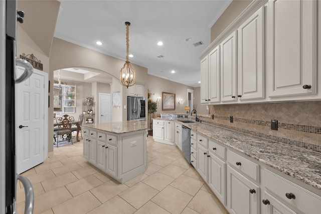 kitchen with appliances with stainless steel finishes, sink, a kitchen island, backsplash, and white cabinets