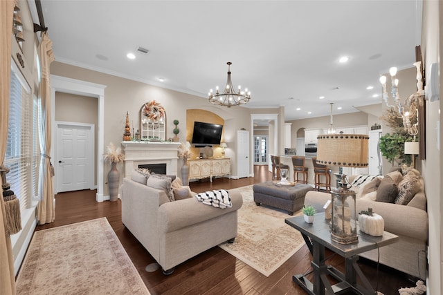 living room with dark wood-type flooring, a notable chandelier, and ornamental molding