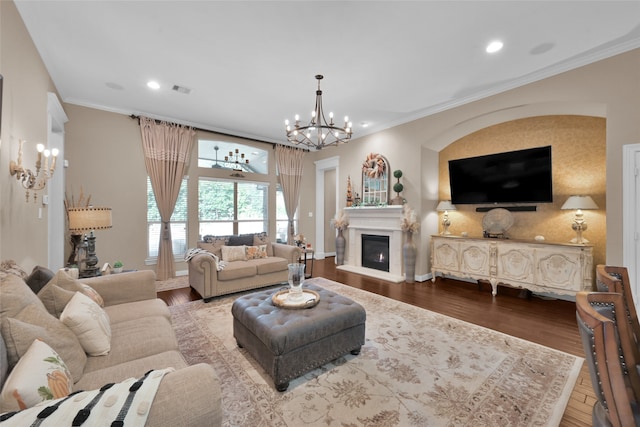 living room with crown molding, wood-type flooring, and an inviting chandelier