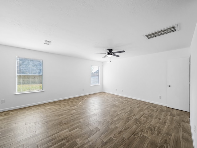 spare room with ceiling fan, a healthy amount of sunlight, and dark hardwood / wood-style floors