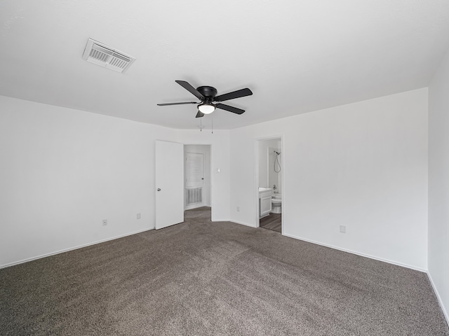 unfurnished bedroom with ensuite bath, dark colored carpet, and ceiling fan