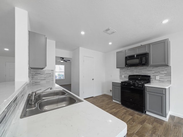 kitchen with dark hardwood / wood-style flooring, black appliances, sink, and gray cabinetry