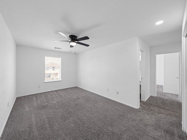 empty room featuring ceiling fan and dark colored carpet