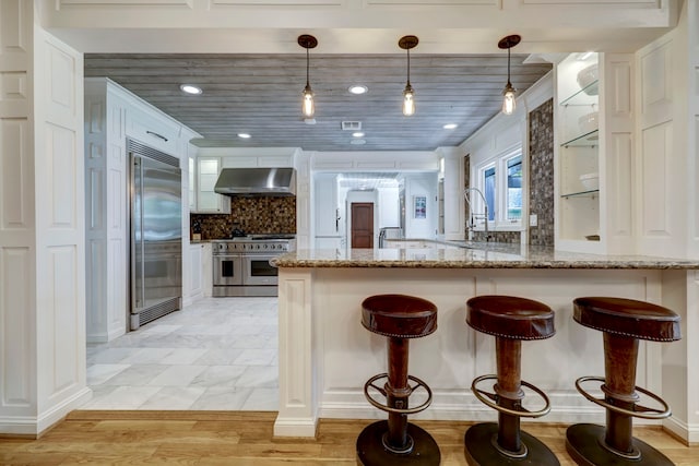 kitchen featuring white cabinets, high quality appliances, exhaust hood, and hanging light fixtures