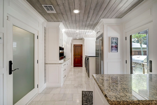 kitchen with stacked washer / dryer, wood ceiling, white cabinetry, appliances with stainless steel finishes, and light stone counters