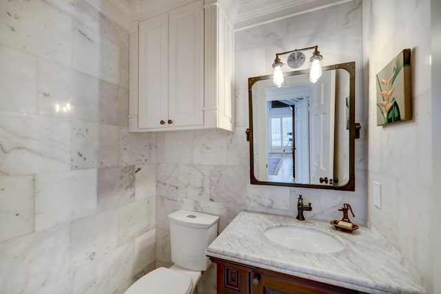 bathroom featuring vanity, toilet, tile walls, and ornamental molding