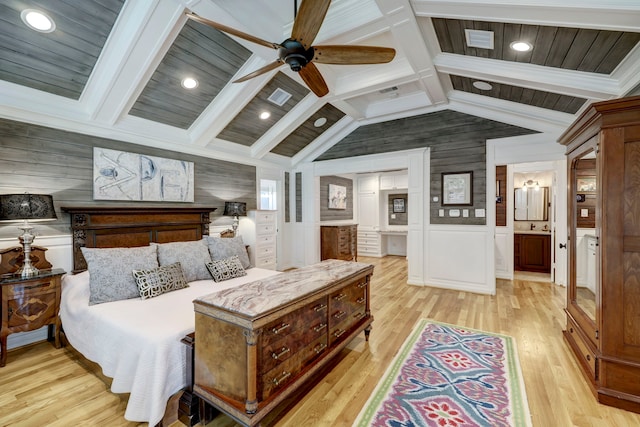 bedroom with connected bathroom, vaulted ceiling with beams, wooden walls, light wood-type flooring, and ceiling fan