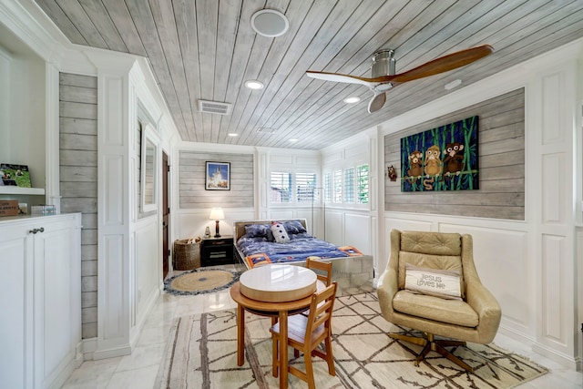 sitting room with wooden walls, wood ceiling, and ceiling fan