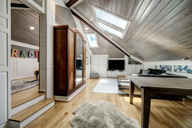 interior space with vaulted ceiling with skylight, wooden walls, wooden ceiling, and light wood-type flooring