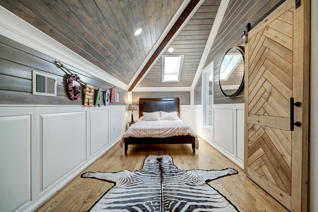 bedroom featuring light hardwood / wood-style floors, wooden ceiling, lofted ceiling, and a barn door