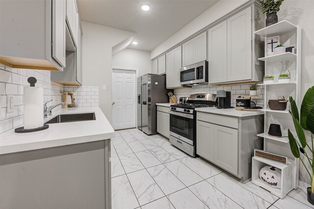 kitchen featuring sink, appliances with stainless steel finishes, decorative backsplash, and gray cabinetry