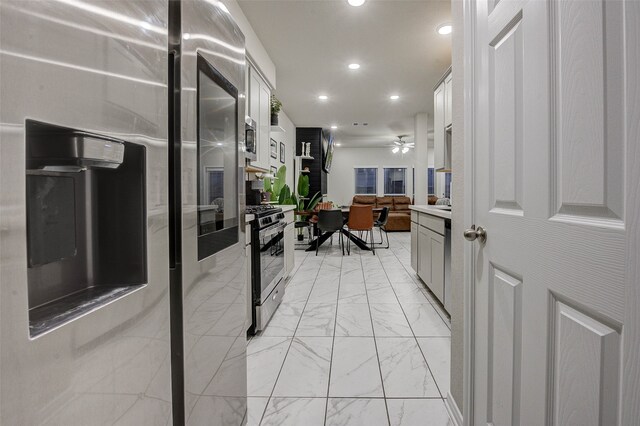 kitchen with appliances with stainless steel finishes, white cabinets, and ceiling fan