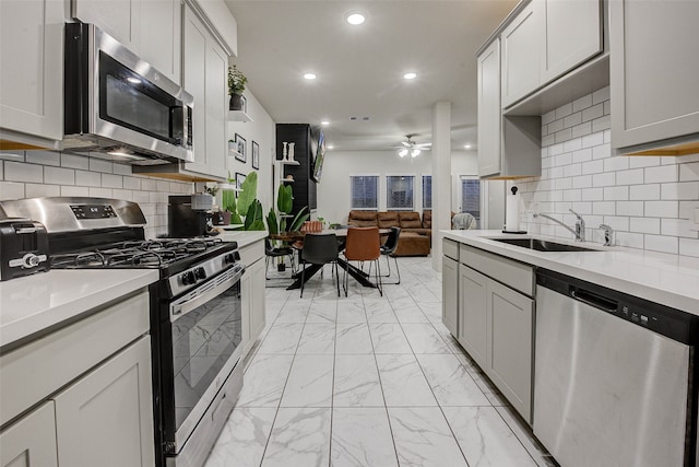 kitchen featuring sink, decorative backsplash, stainless steel appliances, and ceiling fan