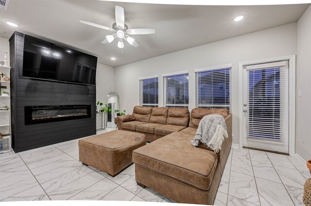 living room featuring a large fireplace and ceiling fan