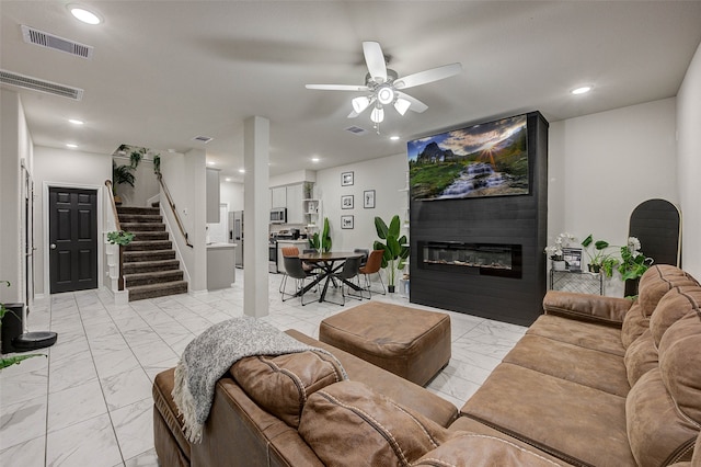 living room featuring a large fireplace and ceiling fan