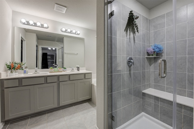 bathroom with vanity, a textured ceiling, a shower with shower door, and tile patterned flooring