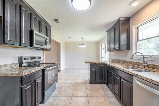 kitchen featuring light tile patterned floors, an inviting chandelier, stainless steel appliances, sink, and decorative light fixtures