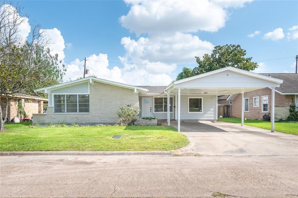 ranch-style house featuring a front lawn and a carport