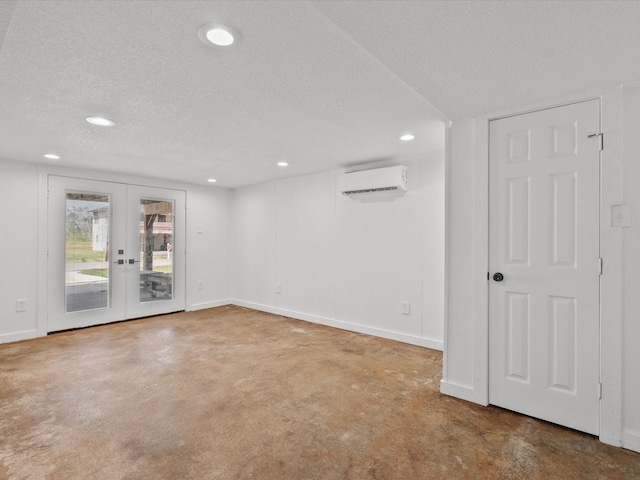 empty room with french doors, a textured ceiling, and a wall mounted air conditioner