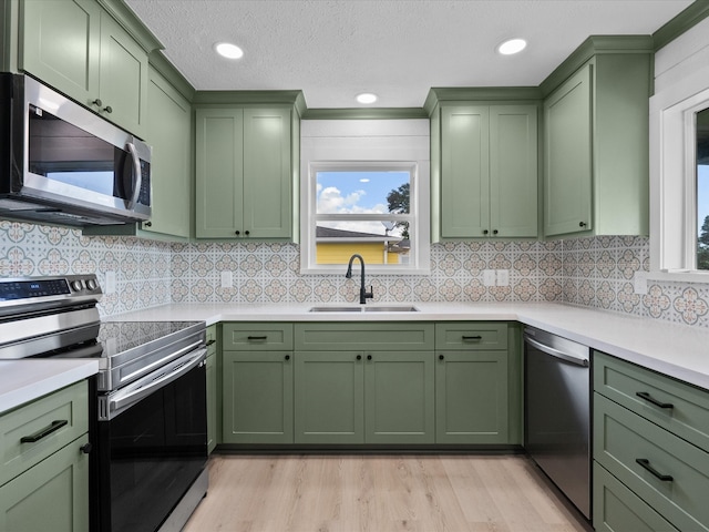 kitchen featuring sink, green cabinetry, decorative backsplash, and stainless steel appliances