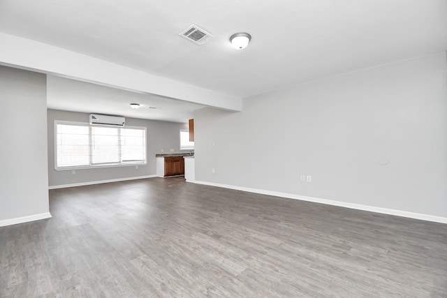 unfurnished living room with beam ceiling, dark hardwood / wood-style flooring, and a wall unit AC