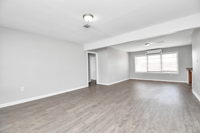 spare room featuring a wall mounted air conditioner and dark wood-type flooring