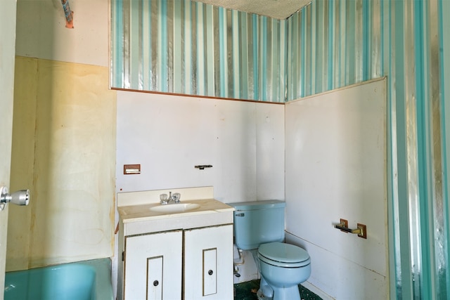 bathroom featuring vanity, a tub to relax in, and toilet