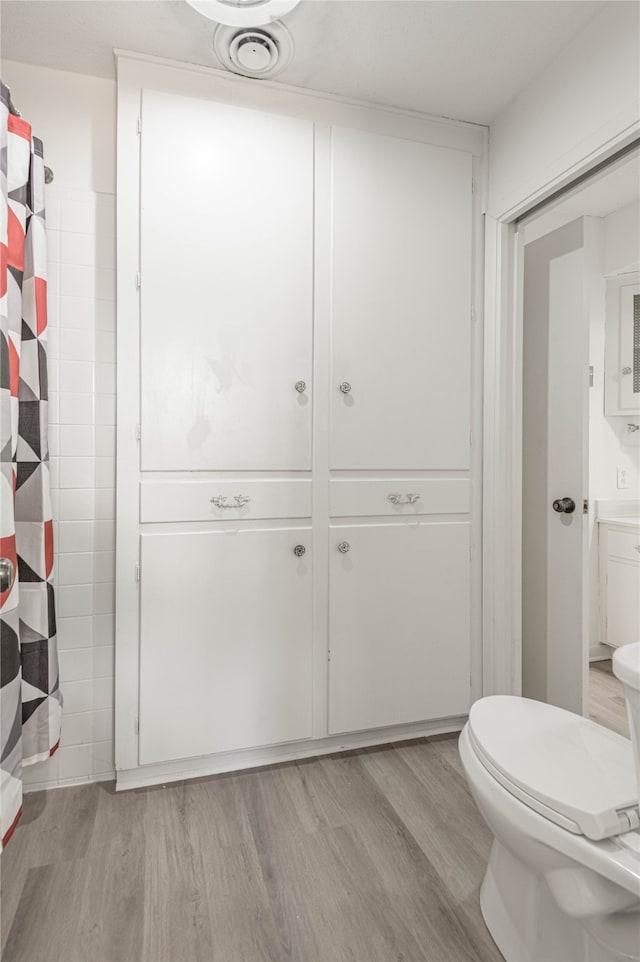 bathroom with wood-type flooring, toilet, and walk in shower