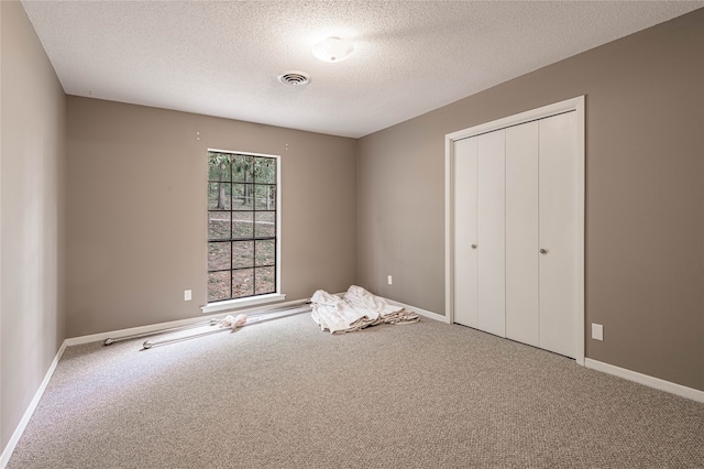 unfurnished bedroom featuring a textured ceiling, a closet, and carpet flooring