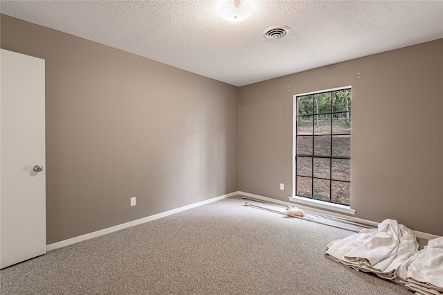 carpeted empty room featuring a textured ceiling