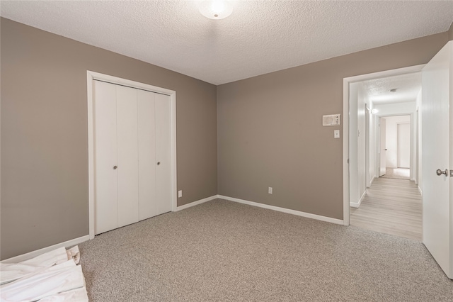 unfurnished bedroom with a closet, a textured ceiling, and light colored carpet