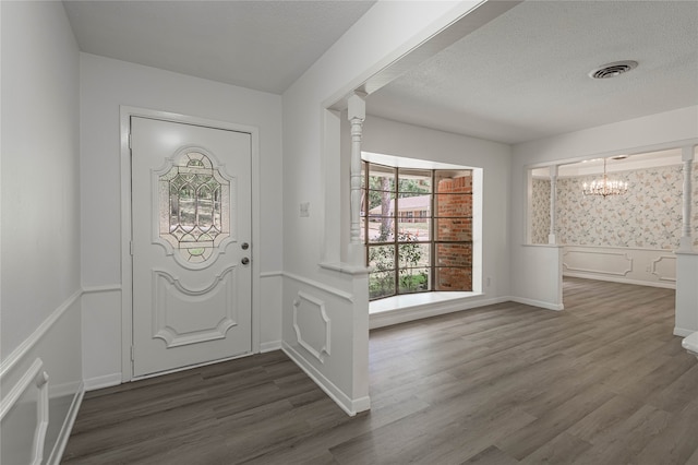 entryway with dark wood-type flooring, a textured ceiling, and an inviting chandelier